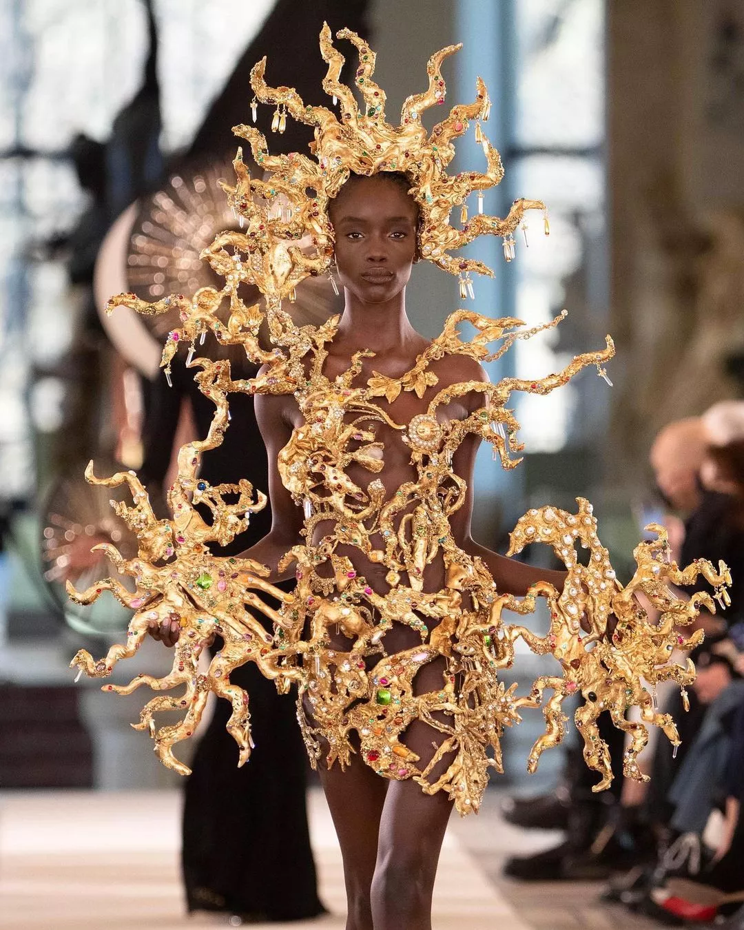 essa foto ilutra uma belíssima modelo com uma roupa dourada